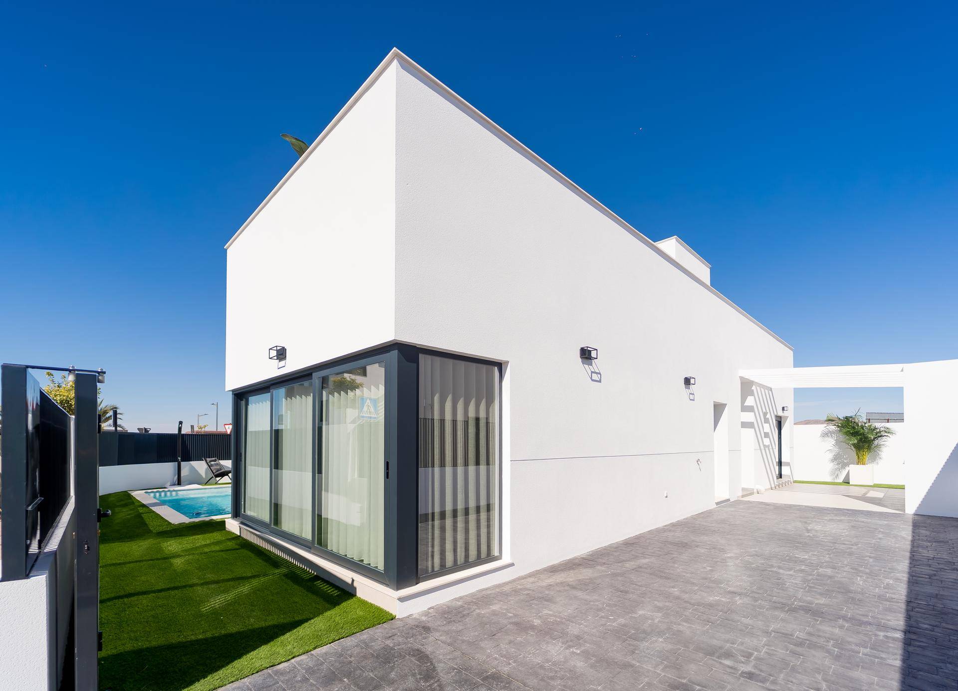 Moderne Hausfassade bei Tag mit gepflasterter Auffahrt und großen Fenstern.