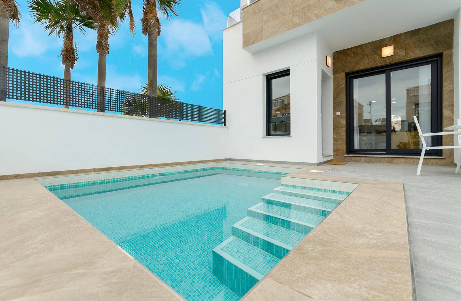 Kleiner, einladender Pool mit Mosaikfliesen und Steineinfassung neben der modernen Villa.