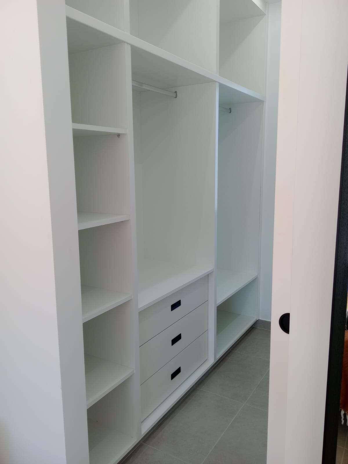 Geräumiger begehbarer Kleiderschrank mit weißen Regalen und Schubladen.