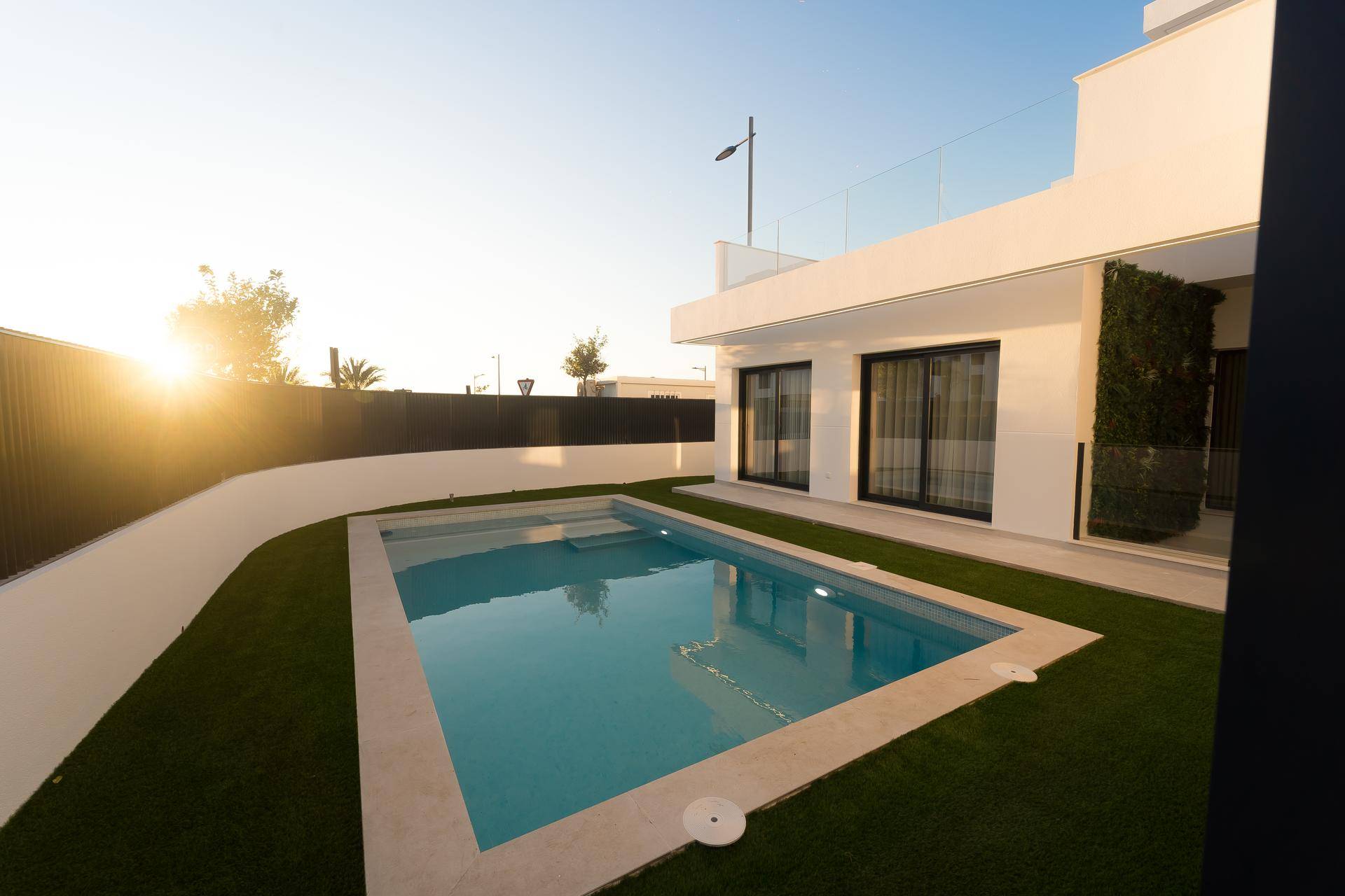 Abendstimmung am privaten Poolbereich mit Rasen und moderner Architektur im Sonnenuntergang.