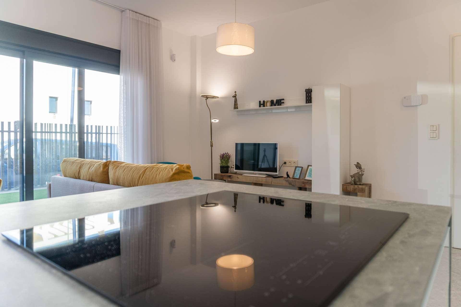 Moderner Wohnbereich mit Induktionskochfeld, Sofa und Blick auf den Außenbereich.