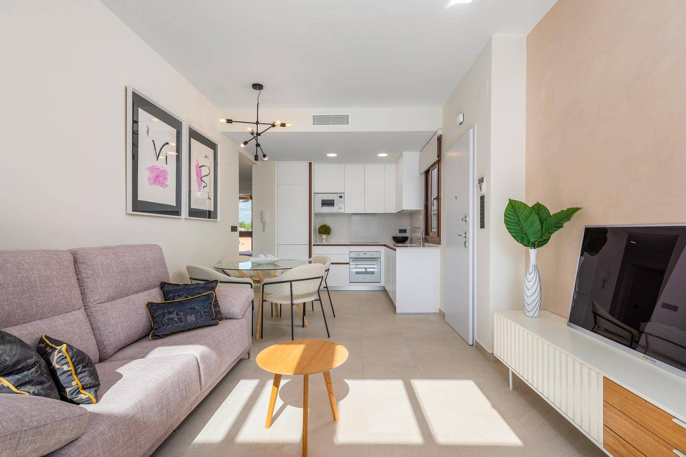 Offener Wohnbereich mit Sofa, Essplatz und integrierter Küche, hell und modern eingerichtet.