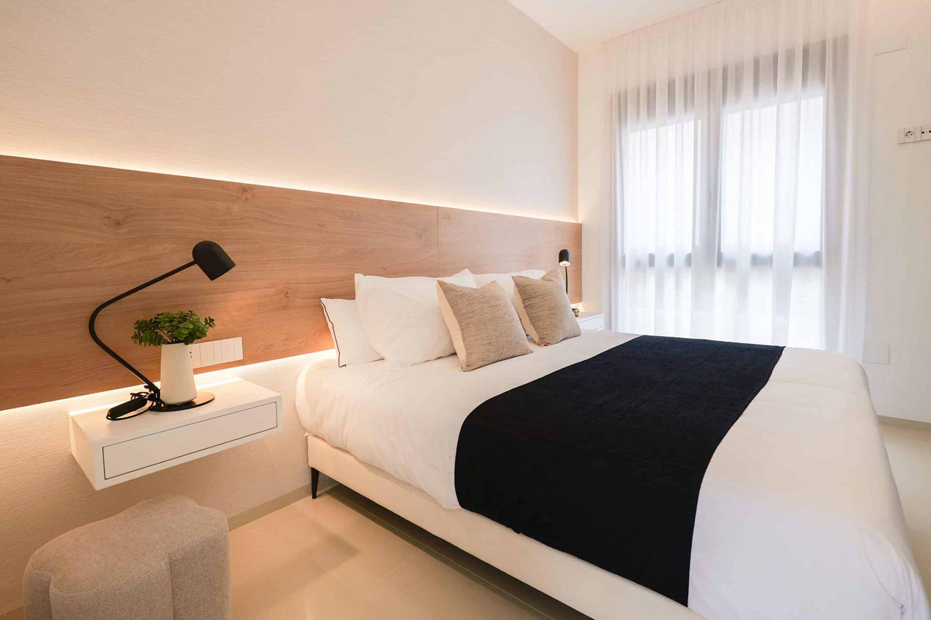 Modernes Schlafzimmer mit großem Fenster, das viel Tageslicht hereinlässt.