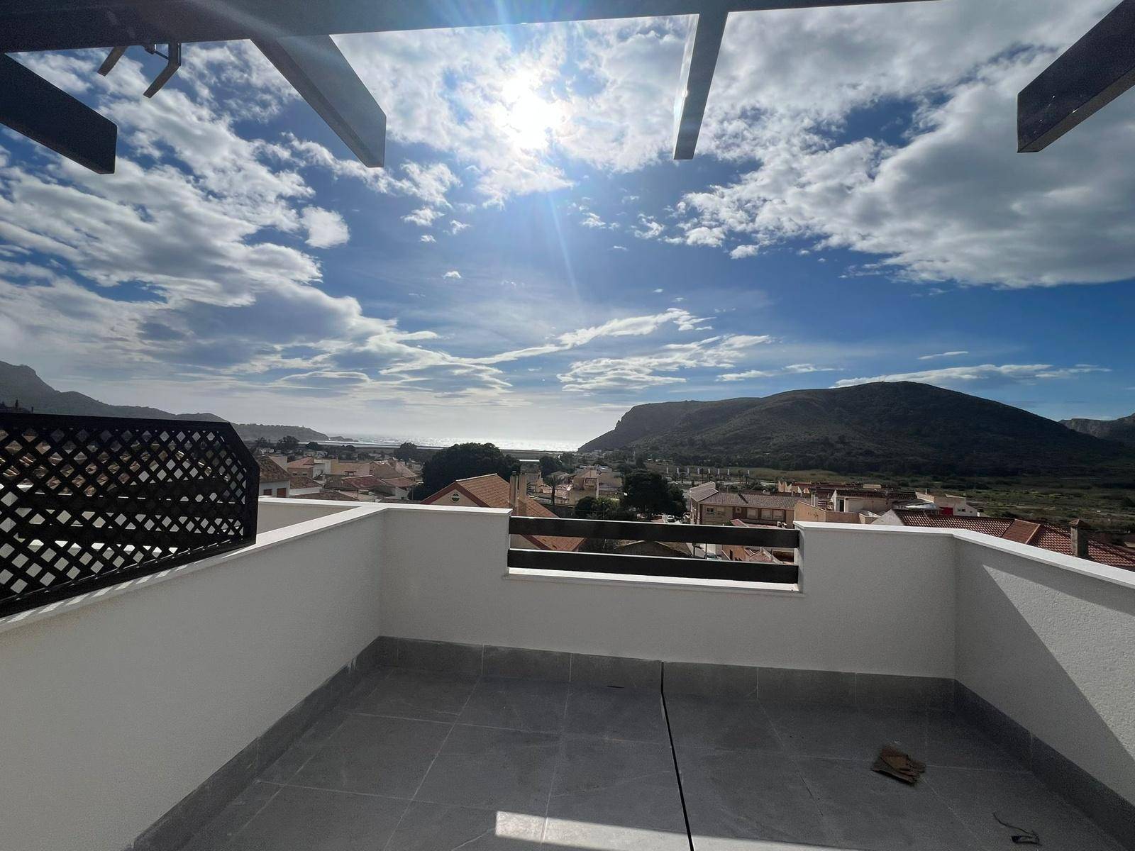Leere Dachterrasse mit Fliesenboden und weitem Blick auf die Stadt, das Meer und die Berge.