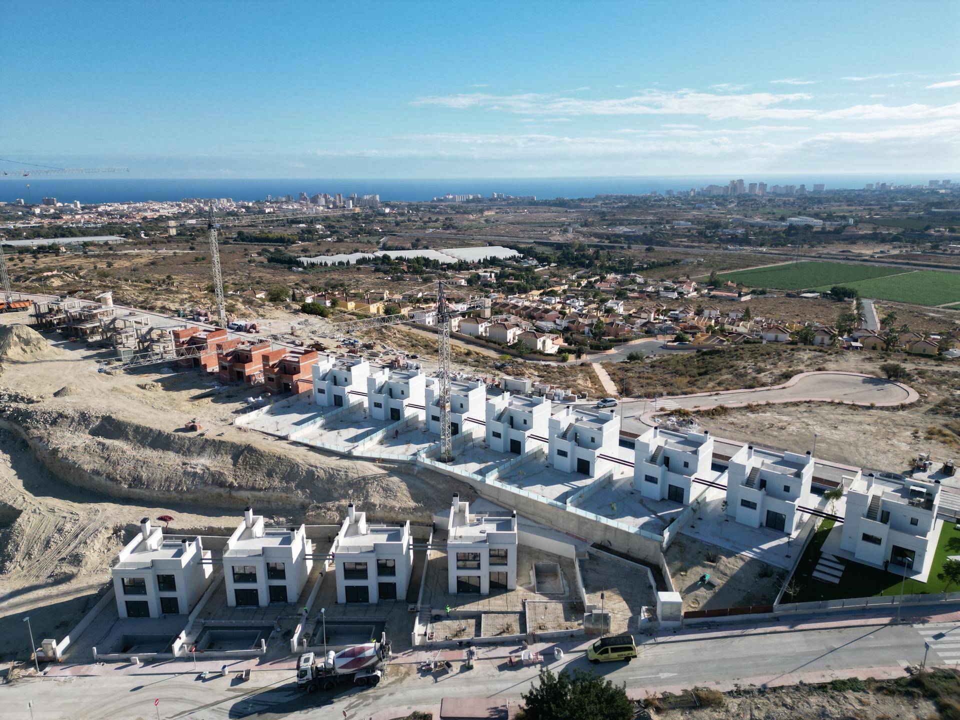 Luftaufnahme einer Neubausiedlung mit modernen Villen und Blick auf die Küste.