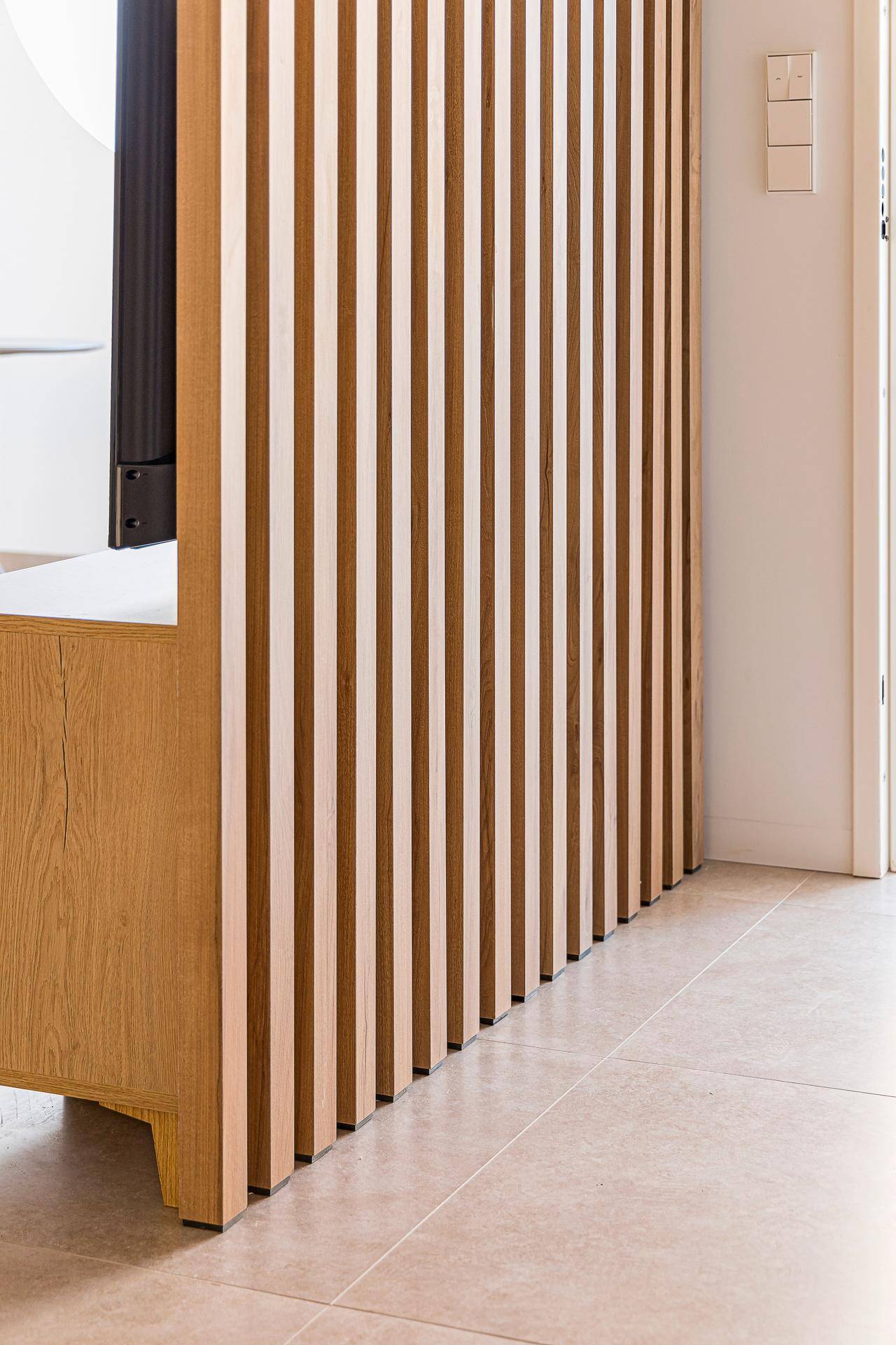 Moderne Holzlamellen-Trennwand im offenen Wohnbereich, die Struktur und Wärme verleiht.