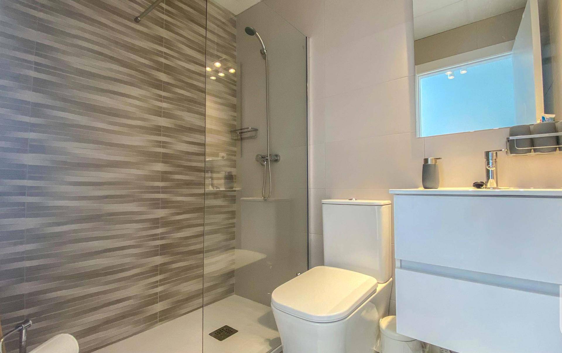 Modernes Badezimmer mit begehbarer Dusche, WC und Waschbecken.