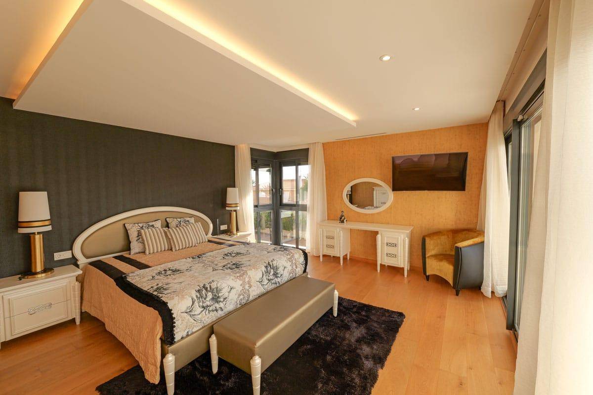 Stilvolles Schlafzimmer mit Holzboden, dekorativer Wandgestaltung und Zugang zum Balkon.