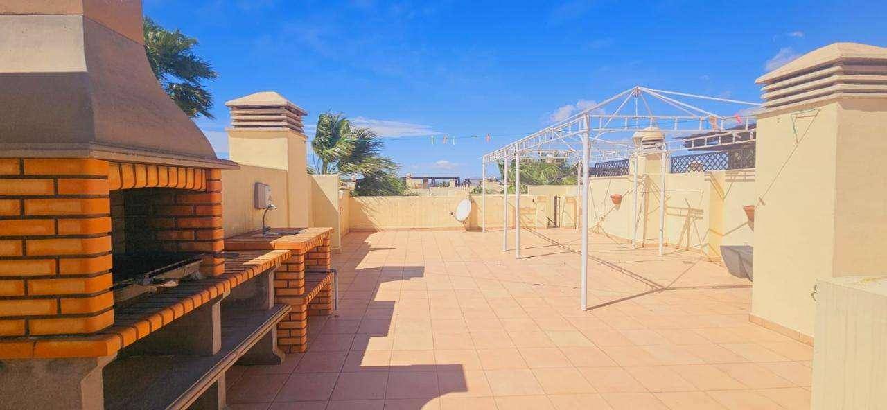 Geräumige Dachterrasse mit Fliesenboden und einer Metallpergola, die Schatten spenden kann.