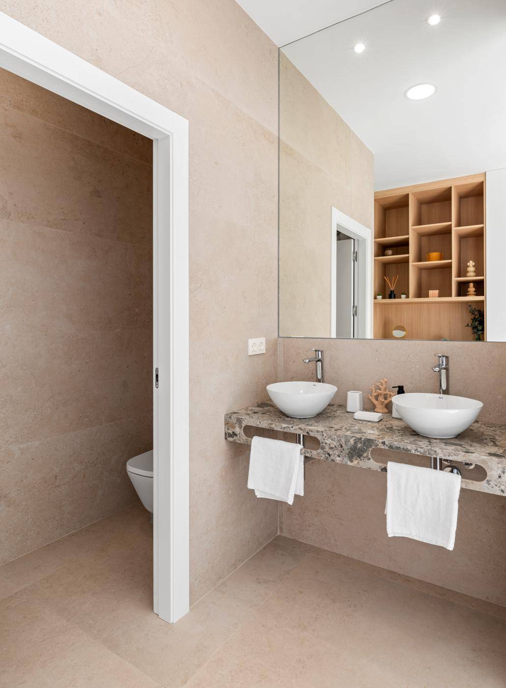 Modernes Badezimmer mit Doppelwaschbecken, großem Spiegel und separatem WC-Bereich.