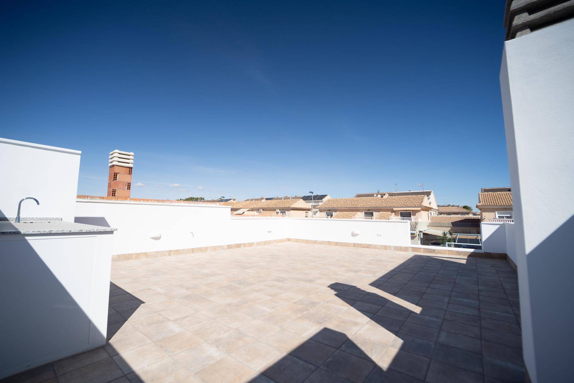 Sonnige Dachterrasse mit Fliesenboden und weitem Blick über die Nachbarschaft.