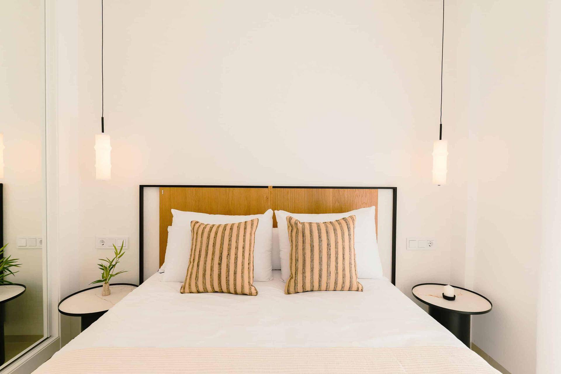 Helles Schlafzimmer mit Holzkopfteil, Nachttischen und Spiegel, modern und einladend gestaltet.