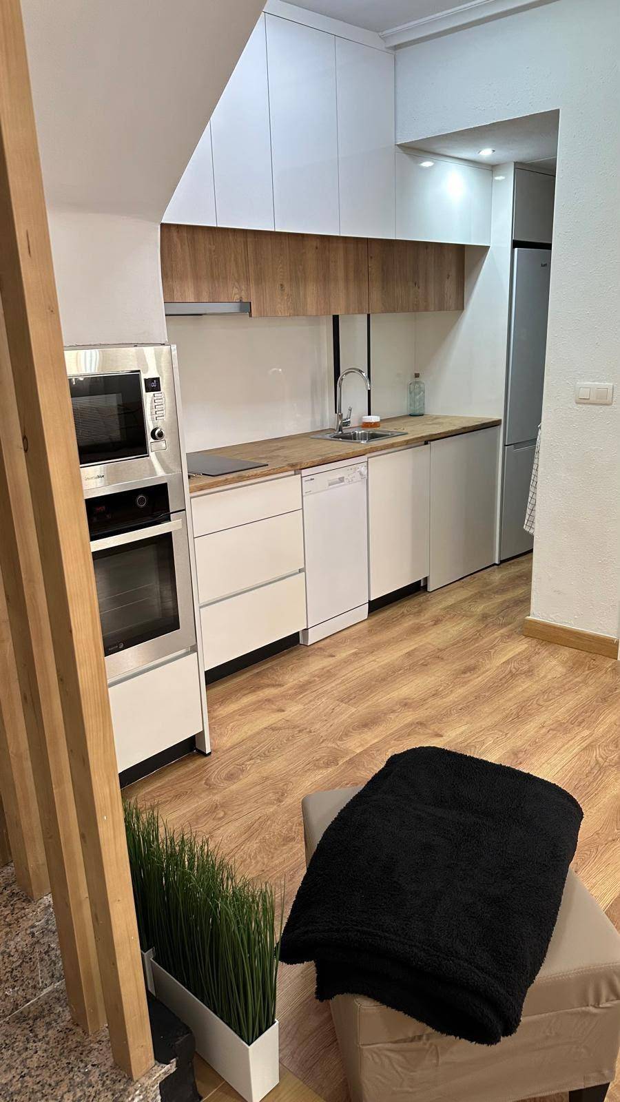 Moderne Küche mit integrierten Geräten und Treppenaufgang, offen zum Wohnbereich.