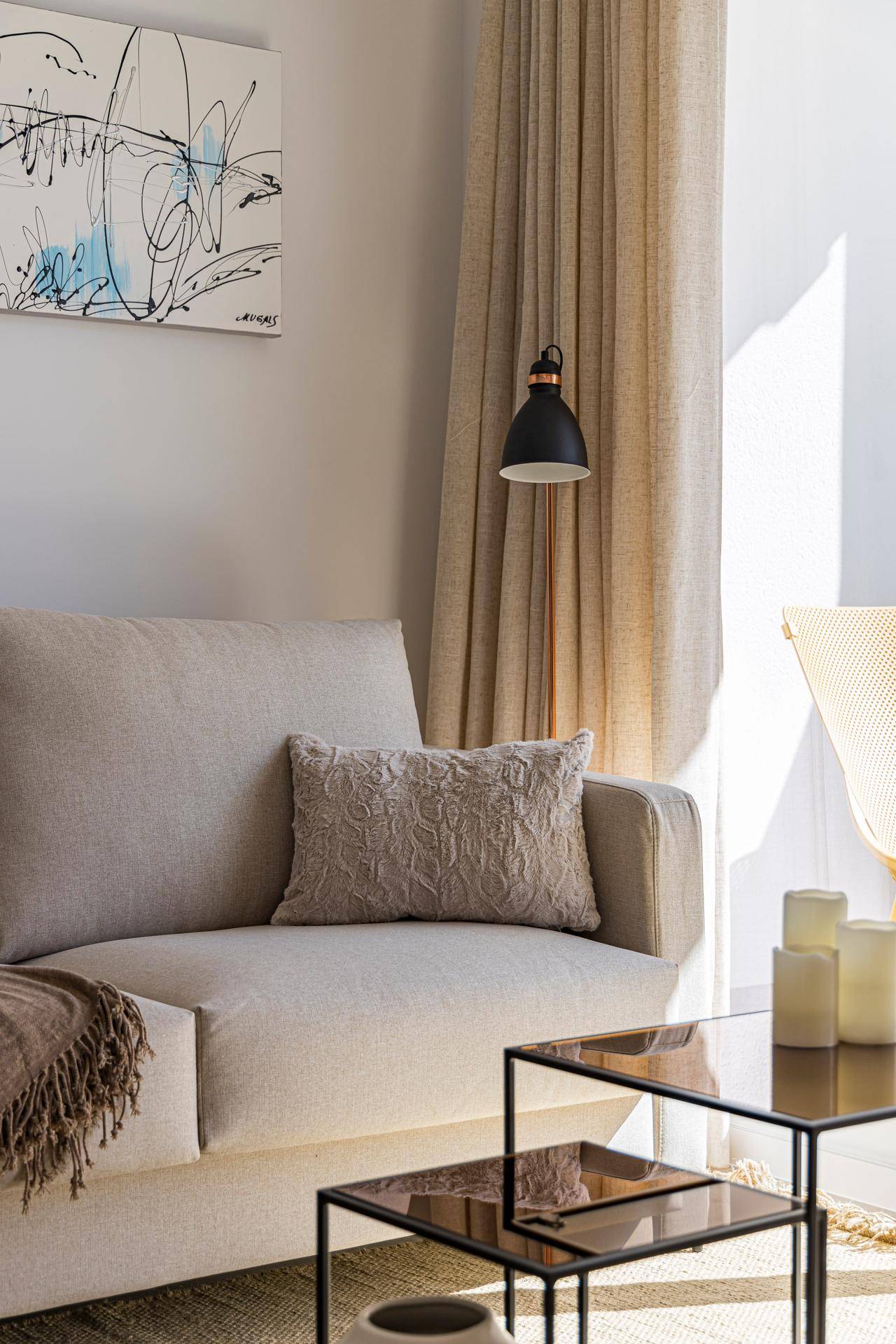 Gemütlicher Wohnbereich mit beigem Sofa, Beistelltischen und indirekter Beleuchtung.