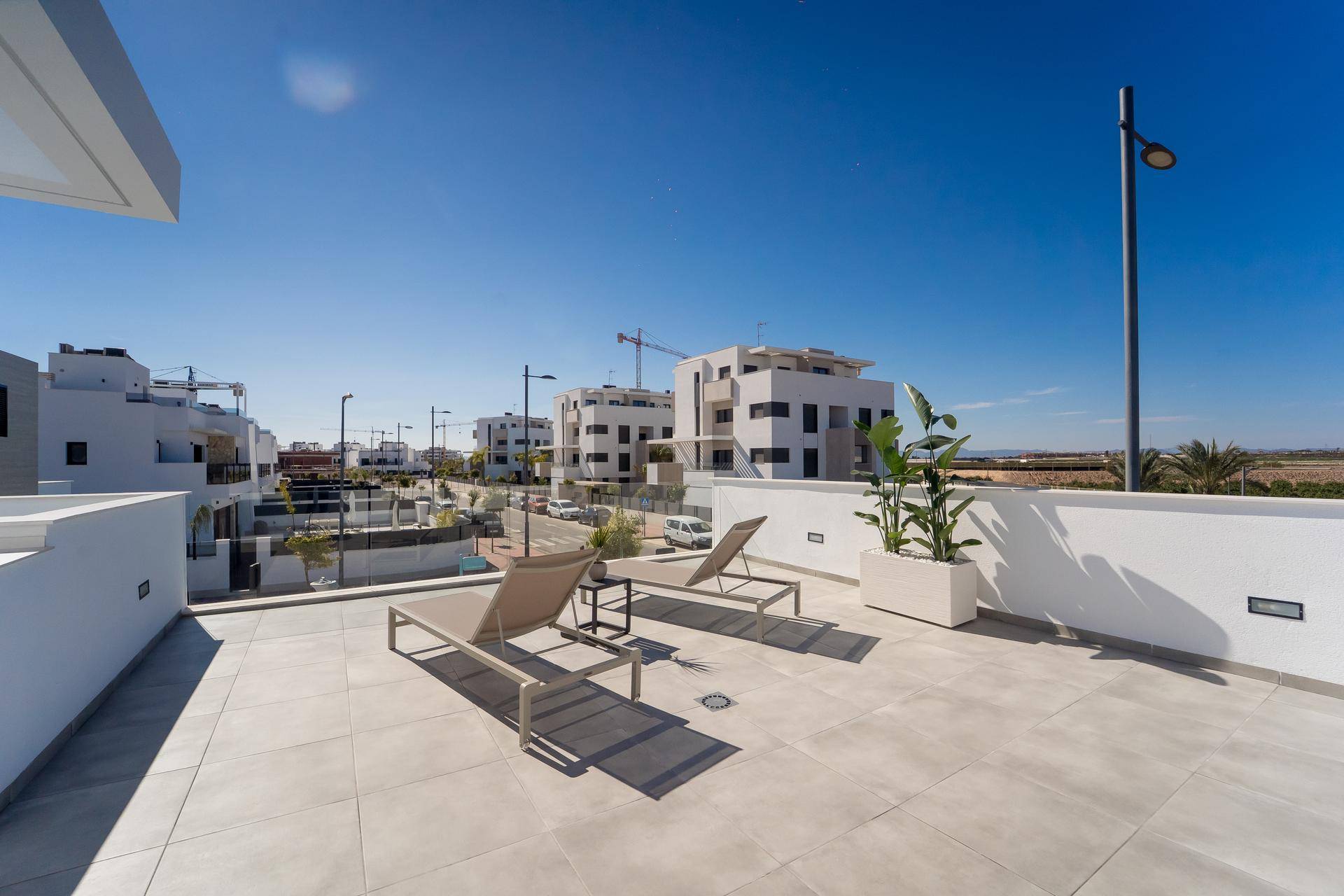 Weitläufige Dachterrasse mit Sonnenliegen und Panoramablick über die Nachbarschaft.