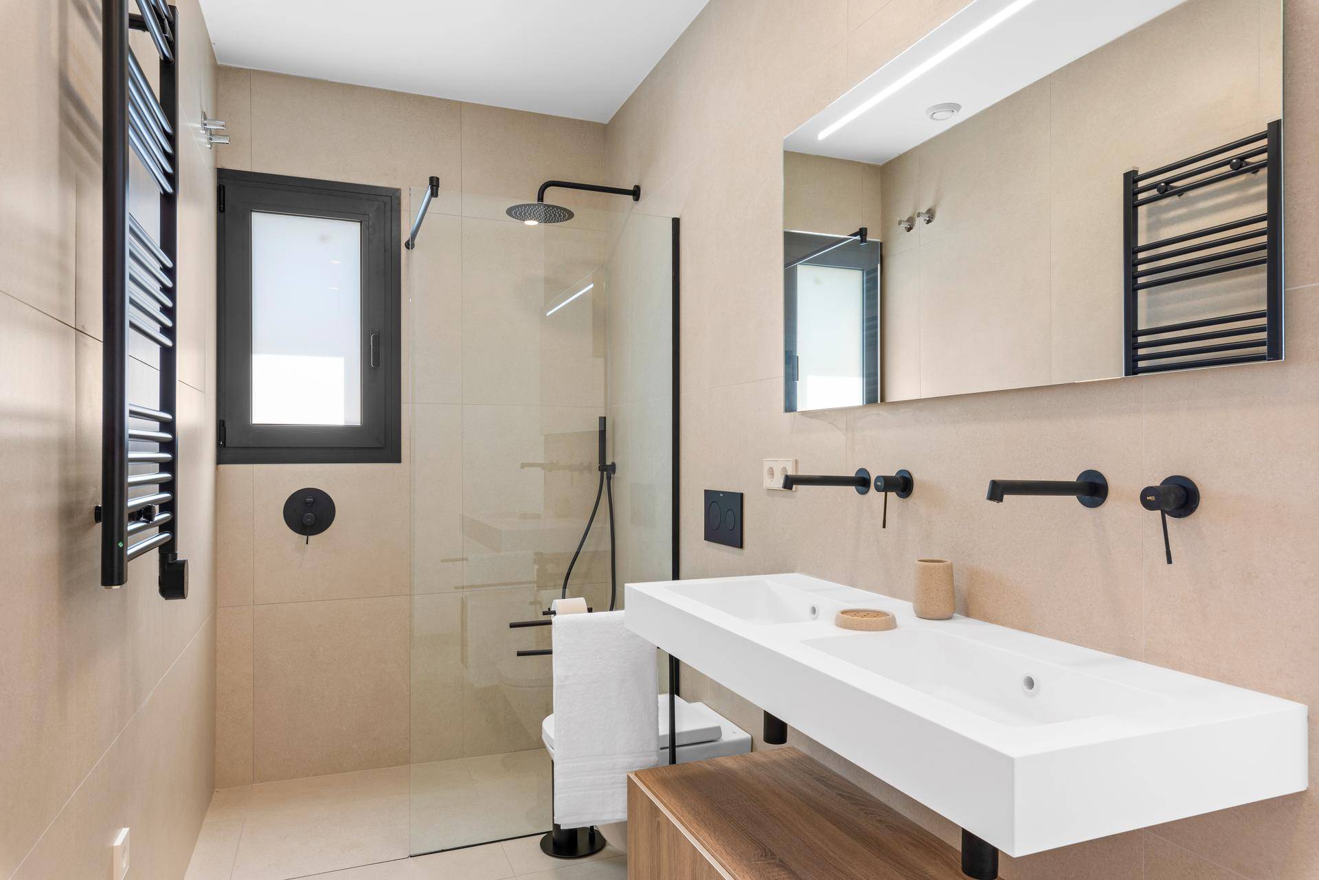Modernes Badezimmer mit Doppelwaschbecken, begehbarer Dusche und beheiztem Handtuchhalter.