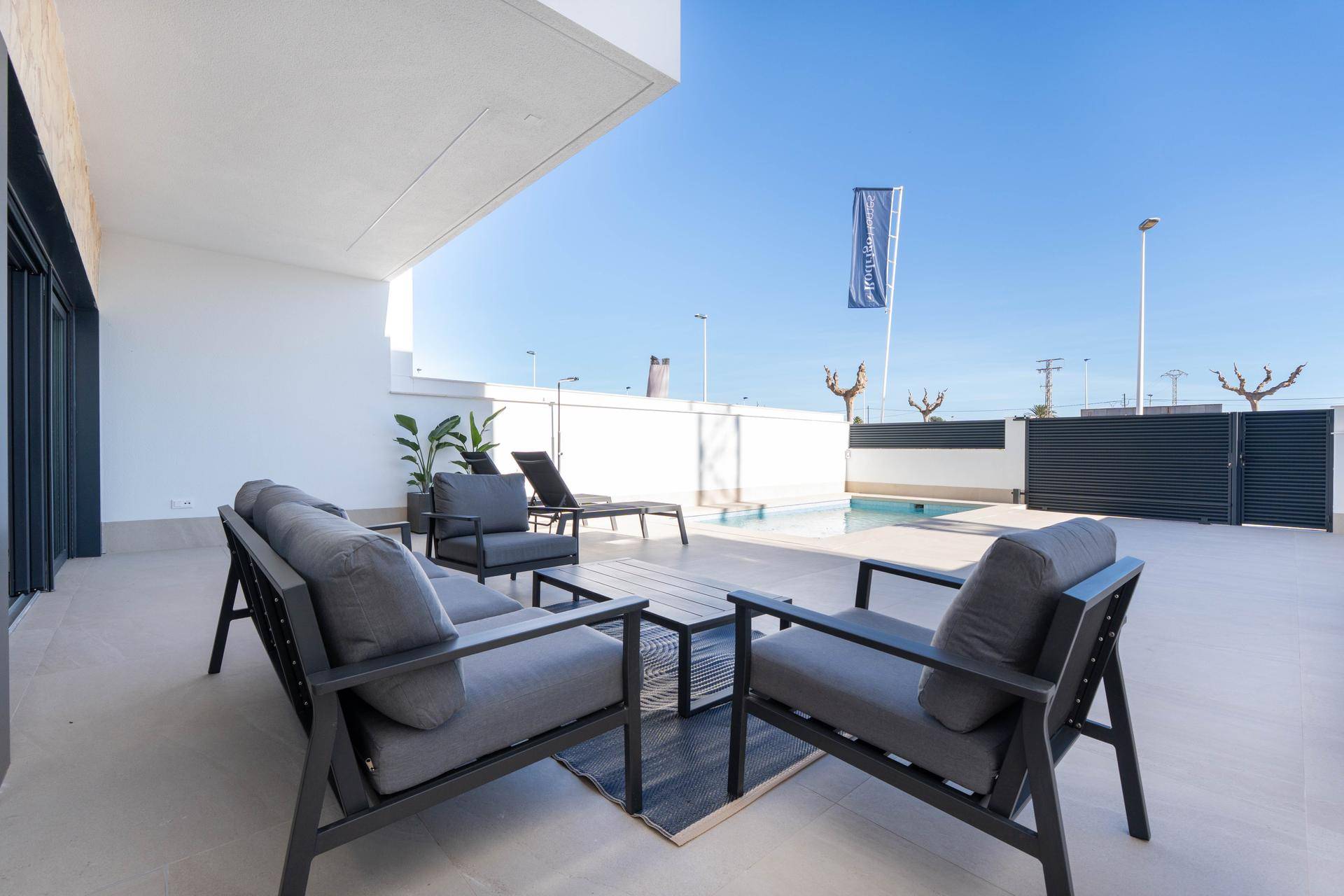Gemütliche Sitzecke auf der Terrasse mit modernen Möbeln und Blick auf den Poolbereich.