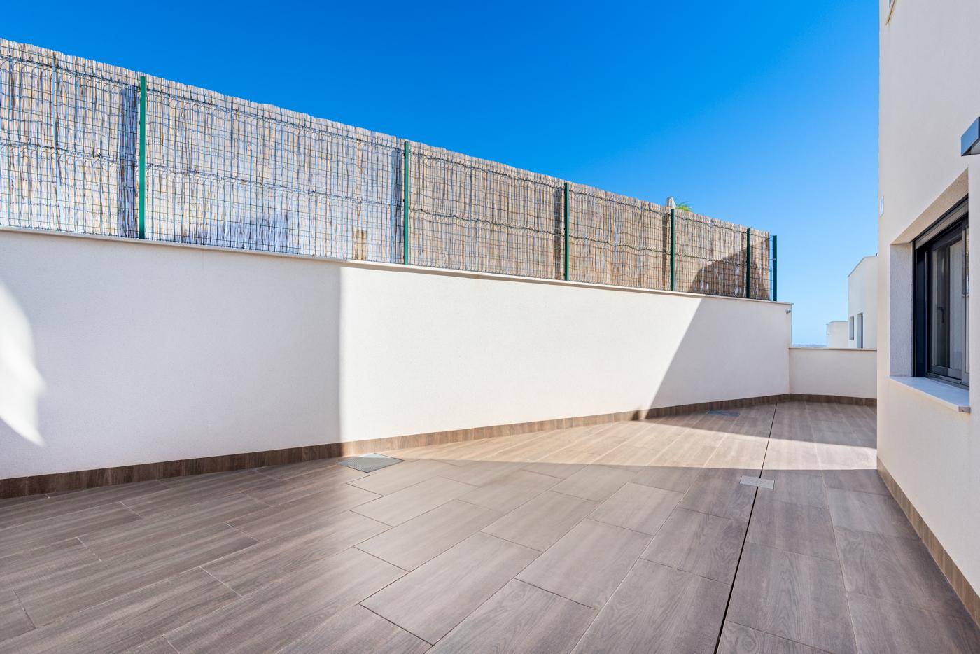 Geräumige, geflieste Terrasse mit hoher Mauer für Privatsphäre und viel Sonne.