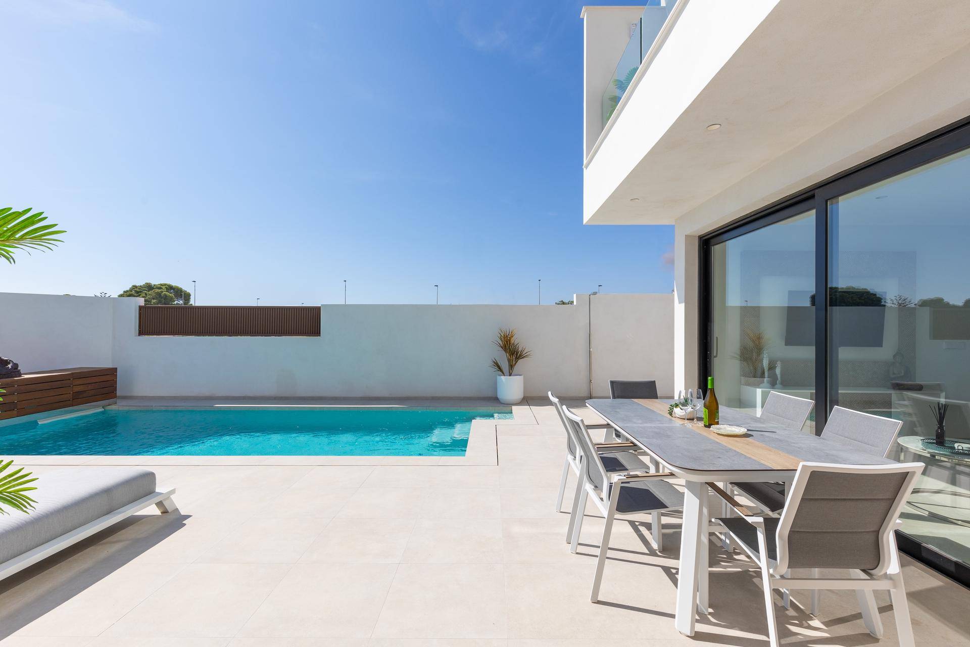 Heller Terrassenbereich mit Esstisch und Pool, ideal für Mahlzeiten im Freien.