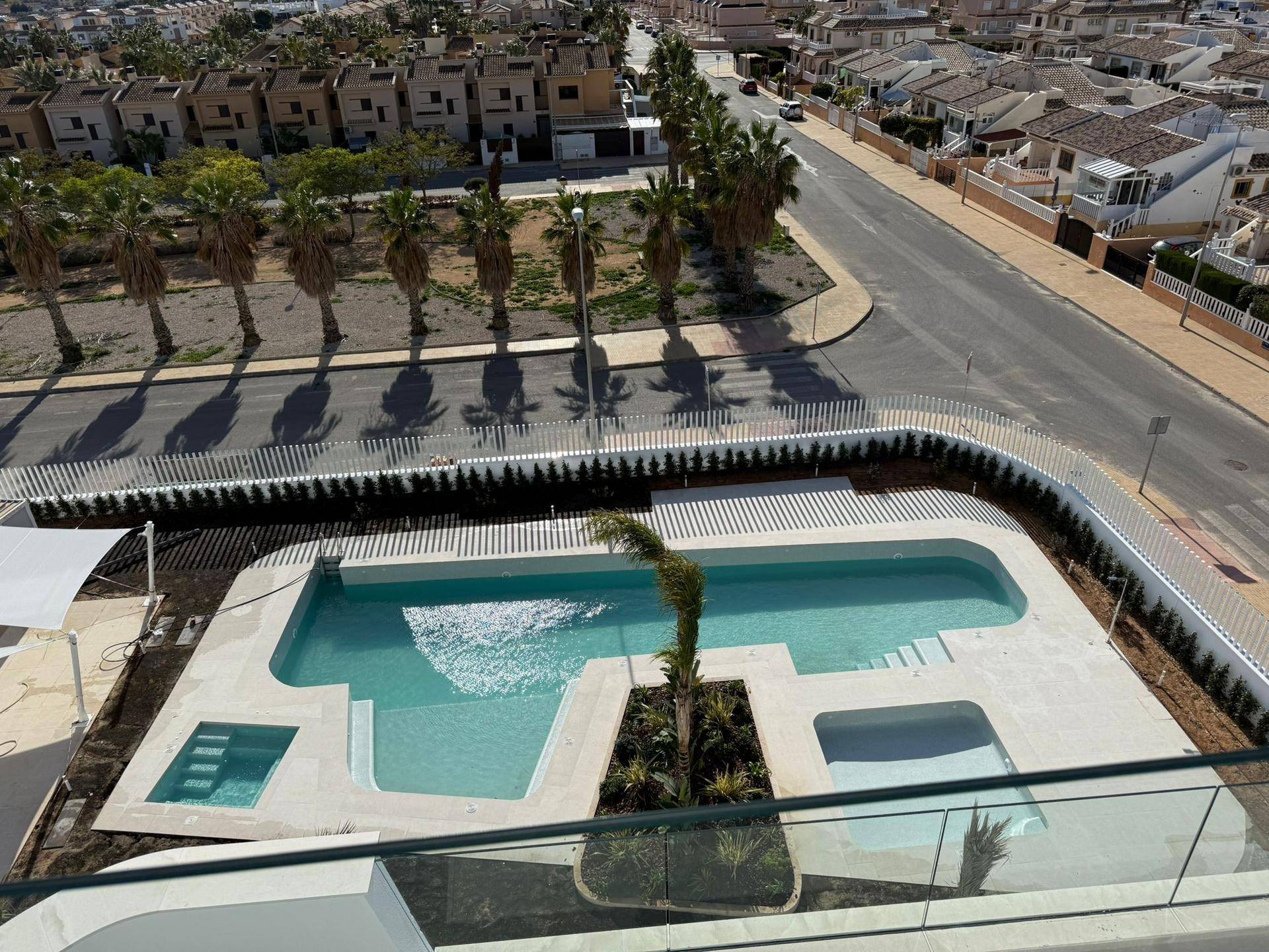 Luftaufnahme eines modernen Apartmentkomplexes mit Poolbereich und umliegender Wohnsiedlung.