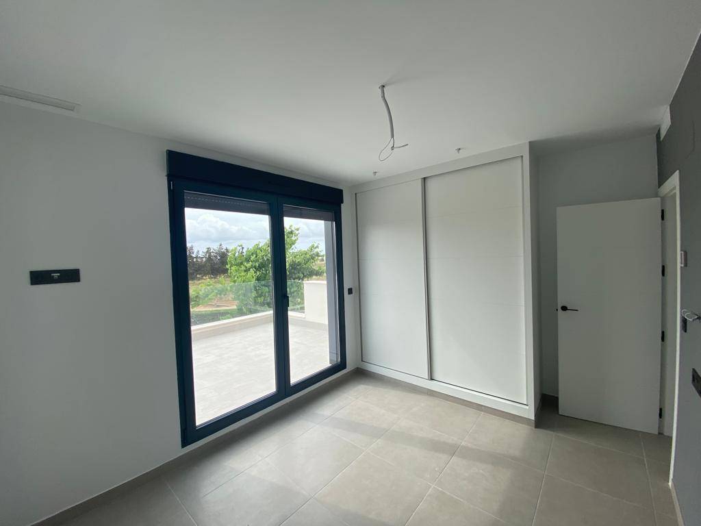 Schlafzimmer mit großem Schiebefenster zum Balkon und integriertem Einbauschrank.