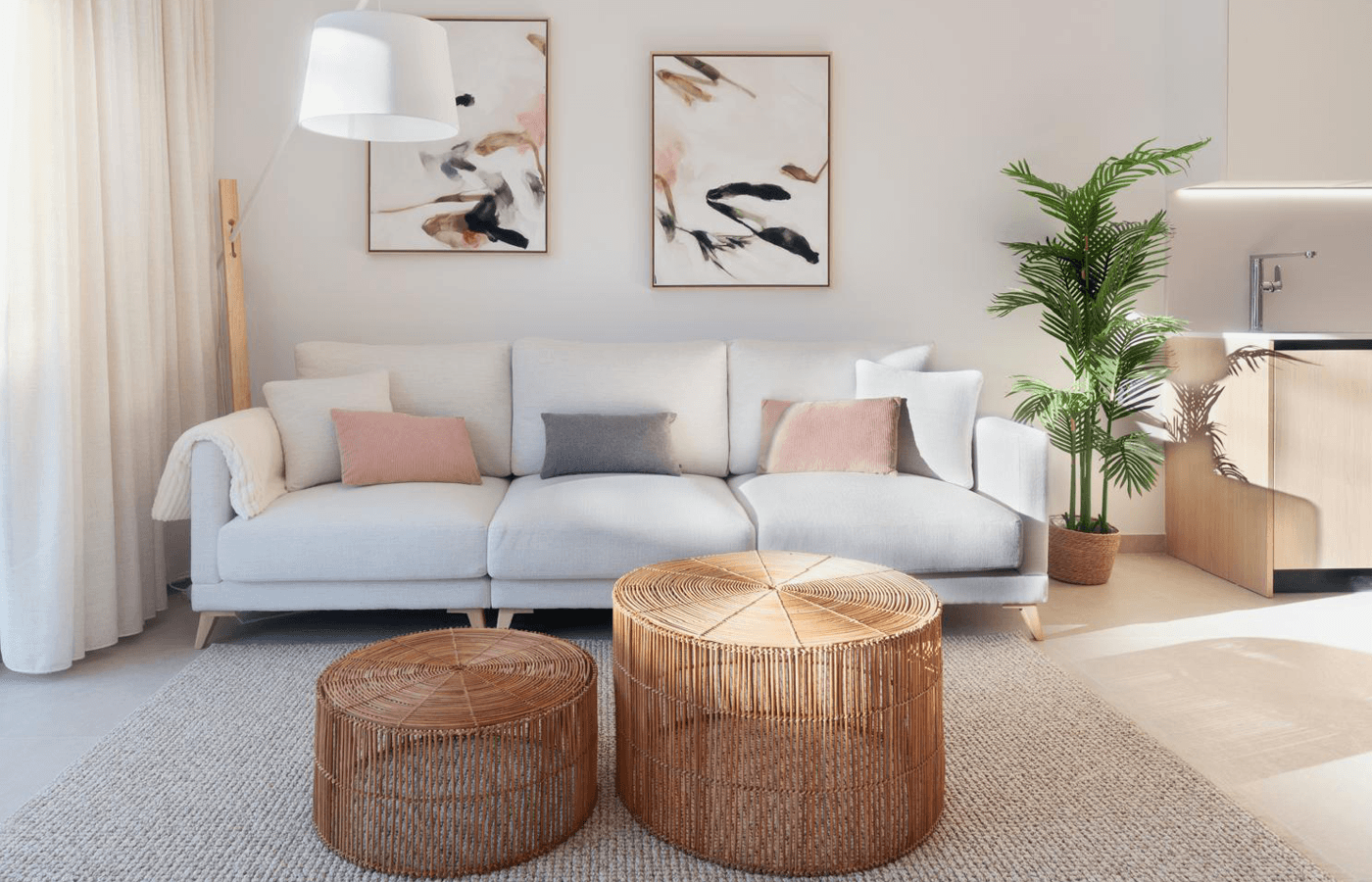 Gemütlicher Wohnbereich mit bequemer Couch, Rattantischen und dekorativen Pflanzen.