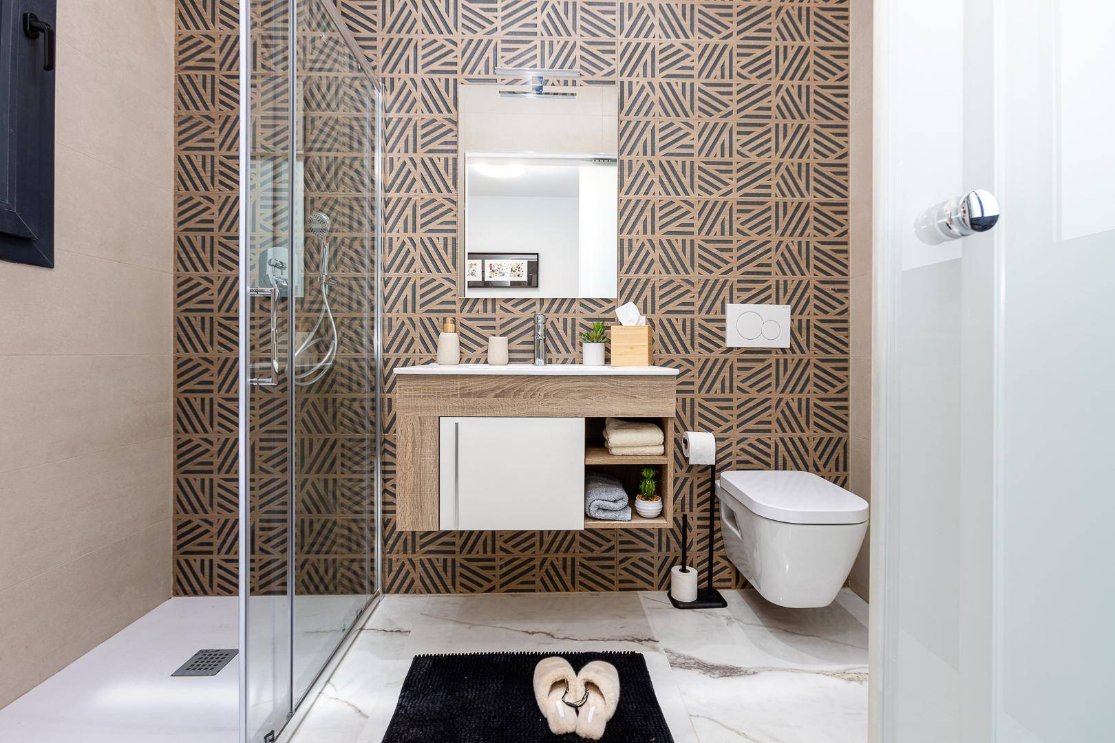 Modernes Badezimmer mit Duschkabine, Hänge-WC und stilvollem Waschtisch mit Ablage.