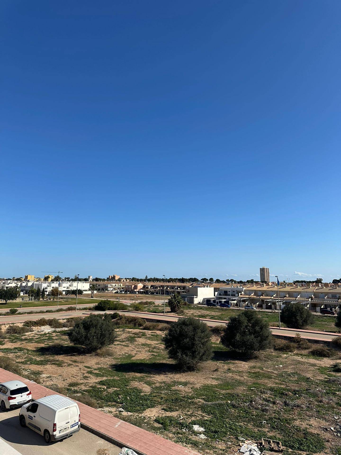 Weitläufiger Blick auf die ländliche Umgebung mit vereinzelten Gebäuden und Vegetation.
