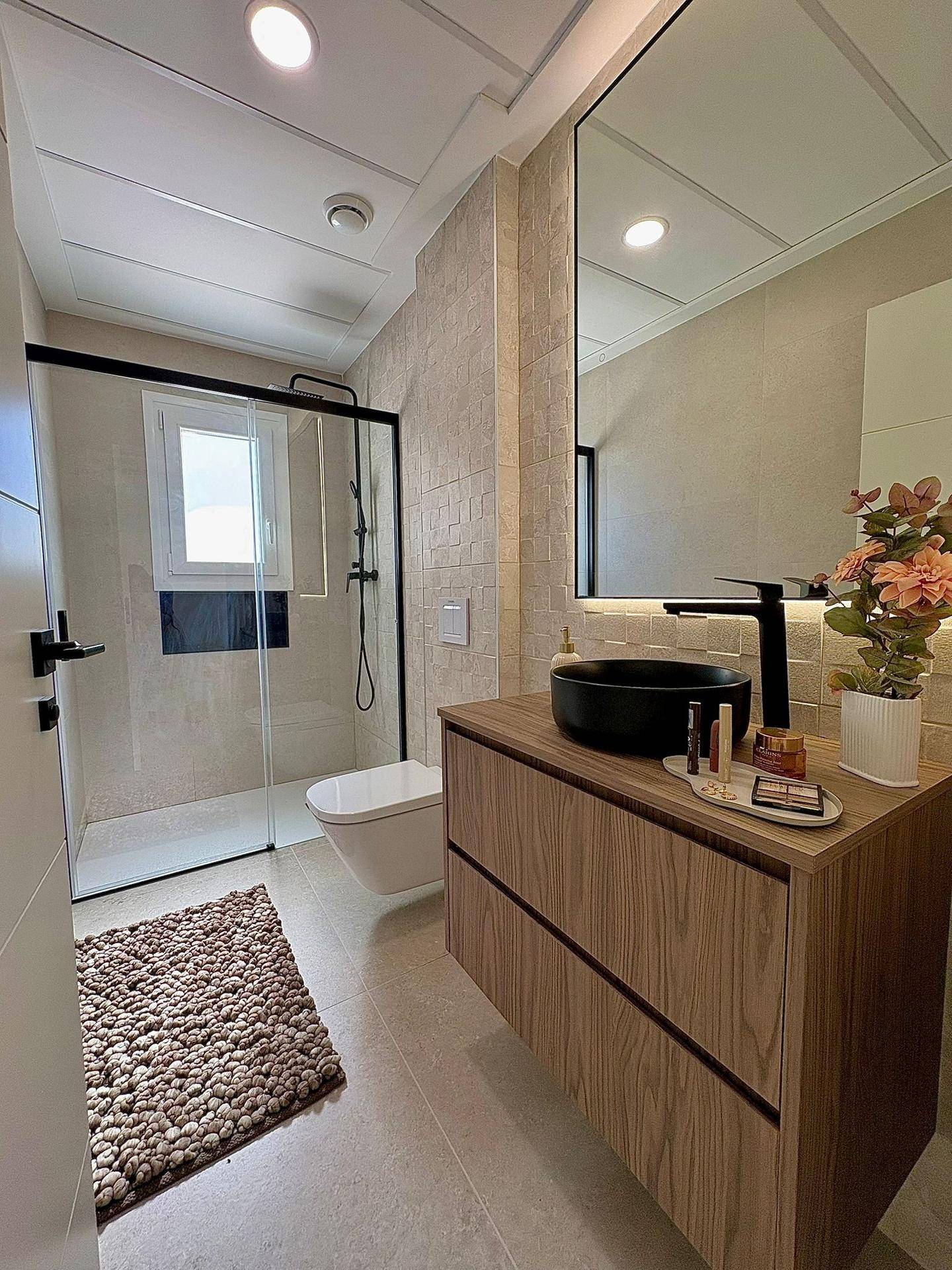 Modernes Badezimmer mit begehbarer Dusche, schwebendem Waschtisch und eleganten schwarzen Armaturen.