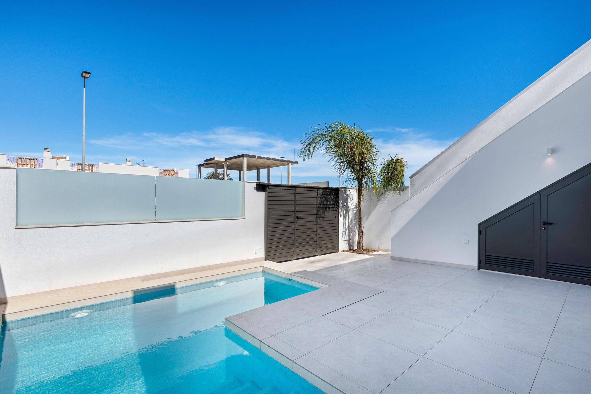 Sonniger Poolbereich mit moderner Architektur und Zugang zu einer Dachterrasse.