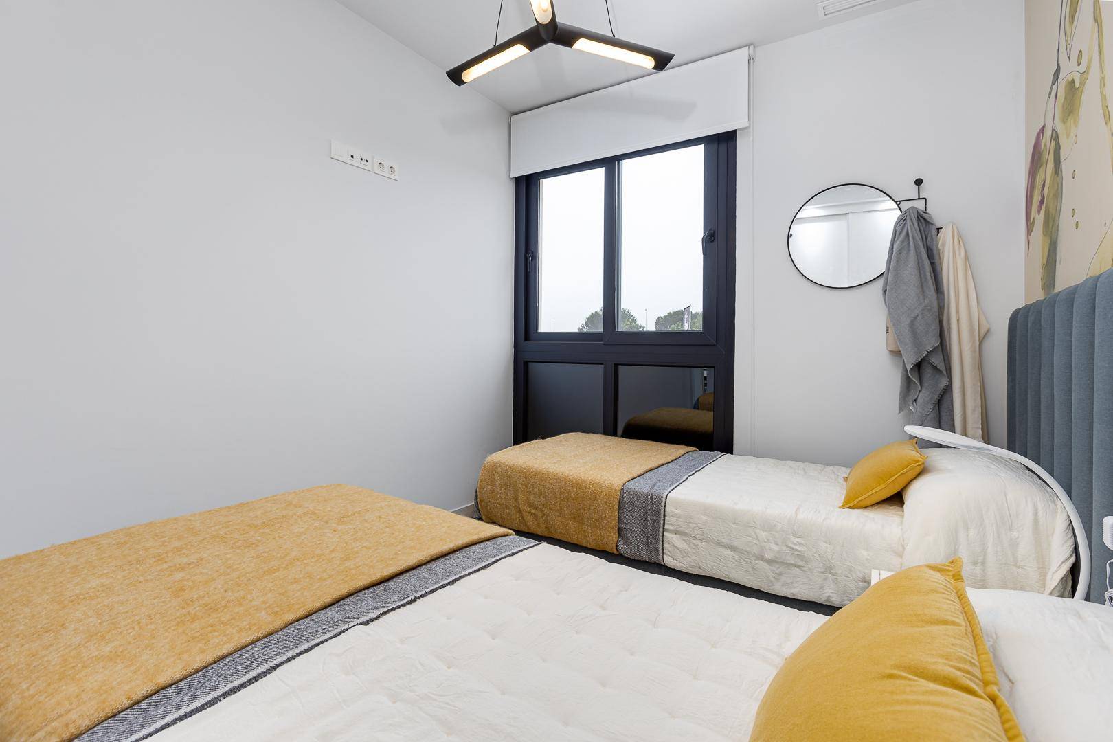 Schlafzimmer mit zwei Einzelbetten, großem Fenster und künstlerischer Wandgestaltung.