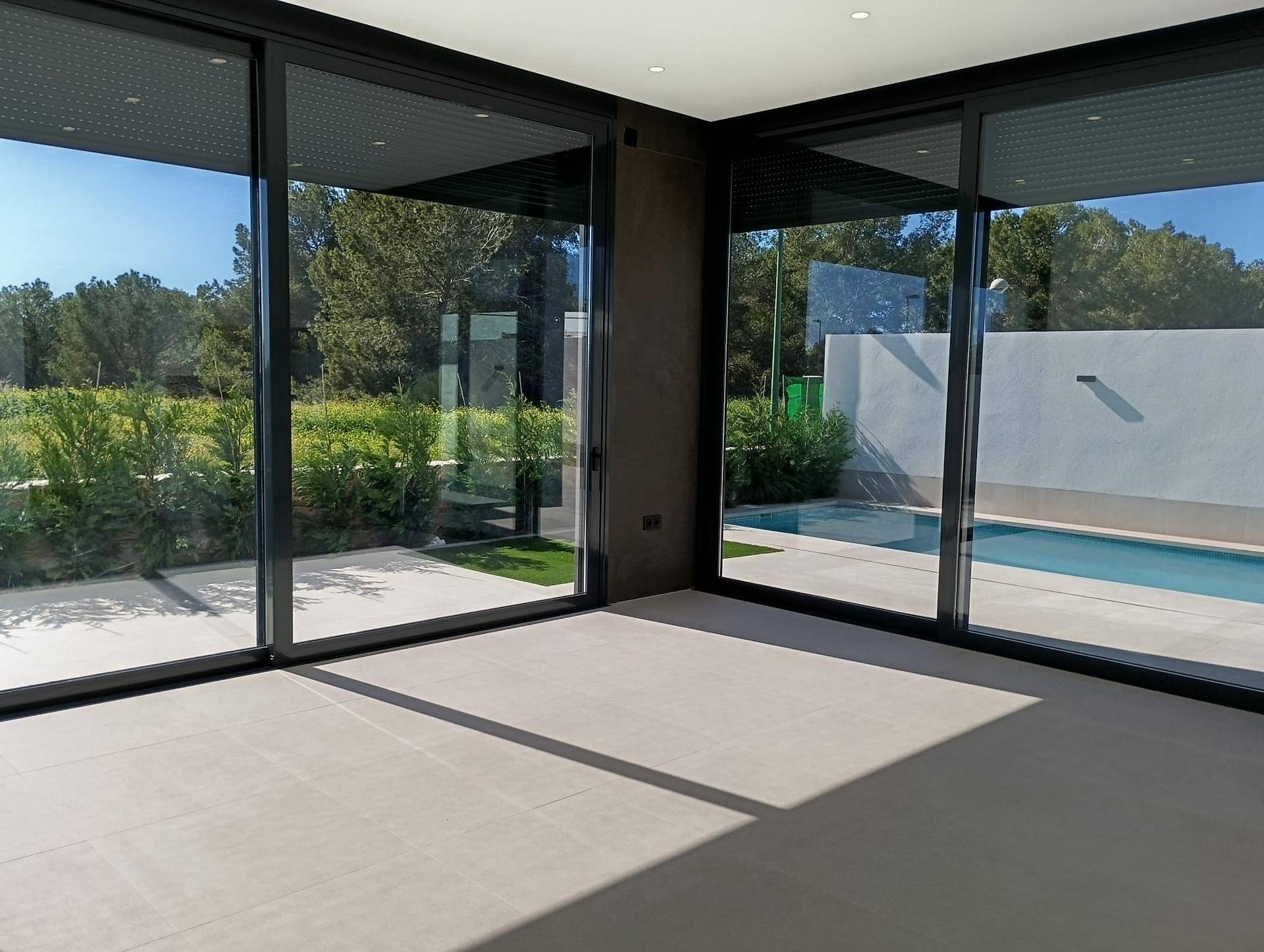 Heller Wohnraum mit großen Schiebetüren, die den Blick auf den Pool und die grüne Umgebung freigeben.