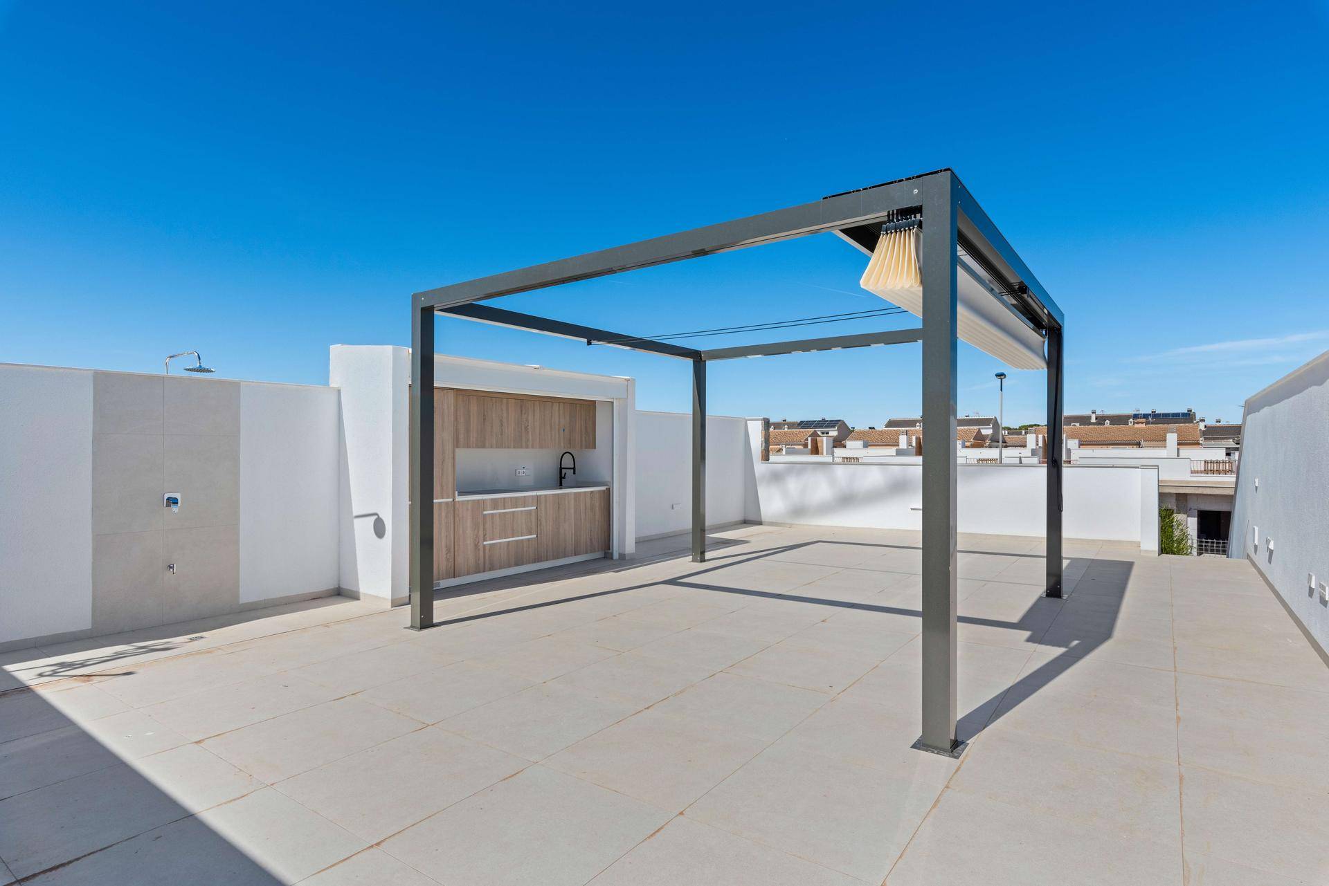 Geräumige Dachterrasse mit Pergola und integrierter Außenküche unter blauem Himmel.