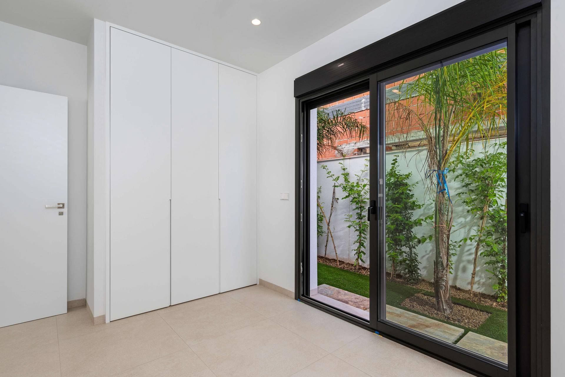 Schlafzimmer mit Einbauschränken und großen Schiebetüren zum grünen Garten.