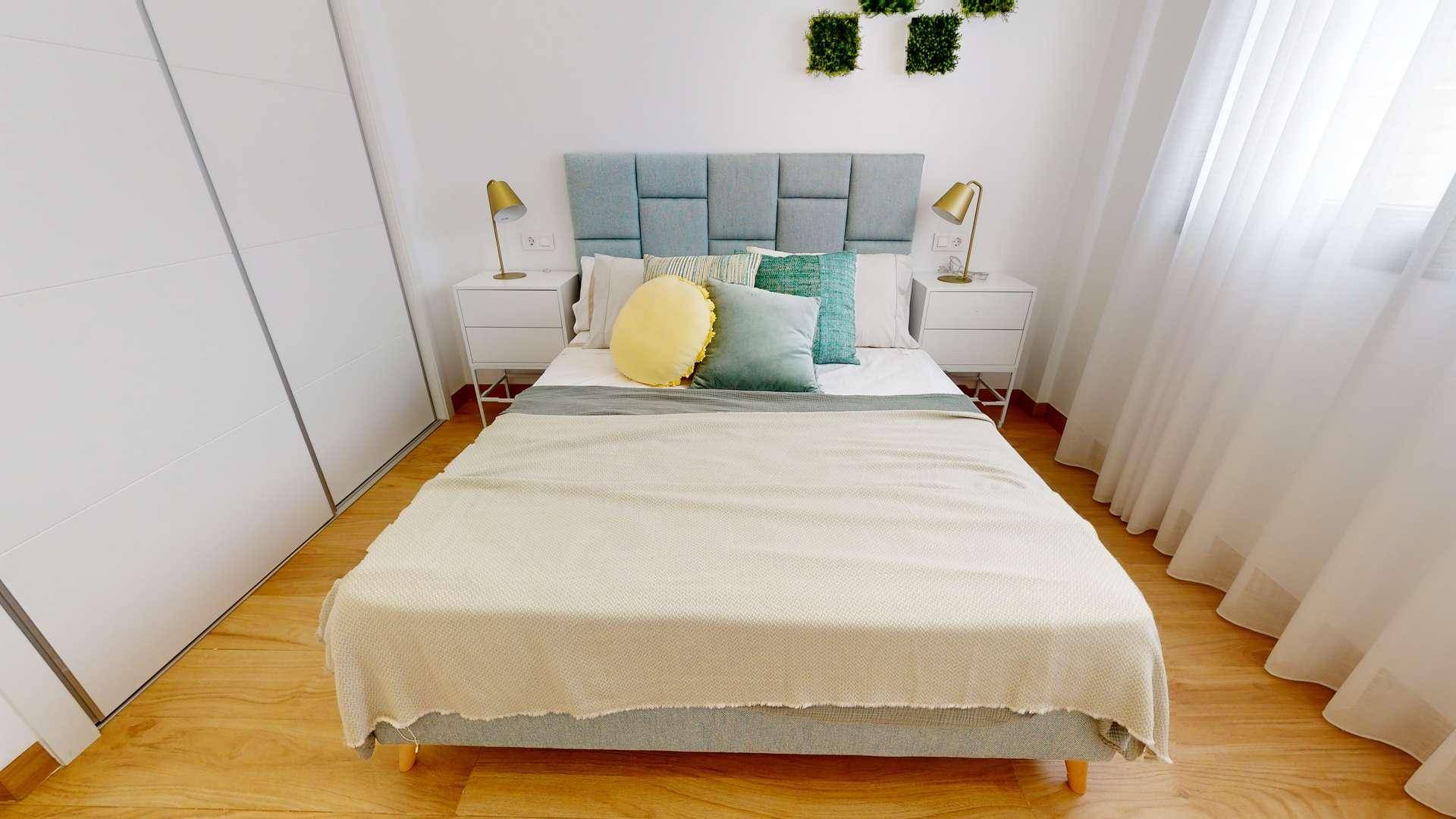 Helles Schlafzimmer mit Doppelbett, Nachttischen und großem Einbauschrank.