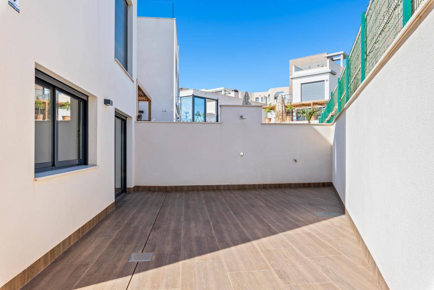 Heller Terrassenbereich mit Fliesenboden und Blick auf die umliegenden Gebäude.