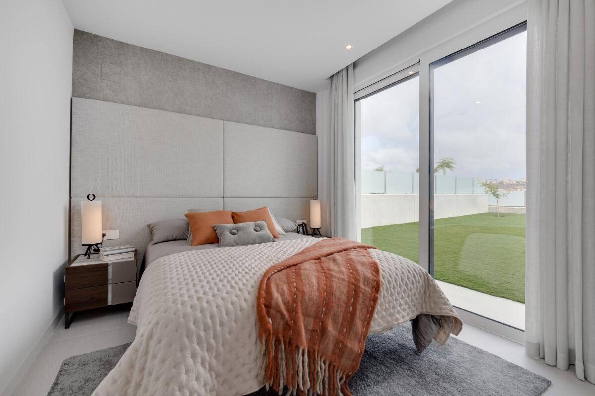 Schlafzimmer mit Zugang zum Garten, großem Fenster und moderner Einrichtung.