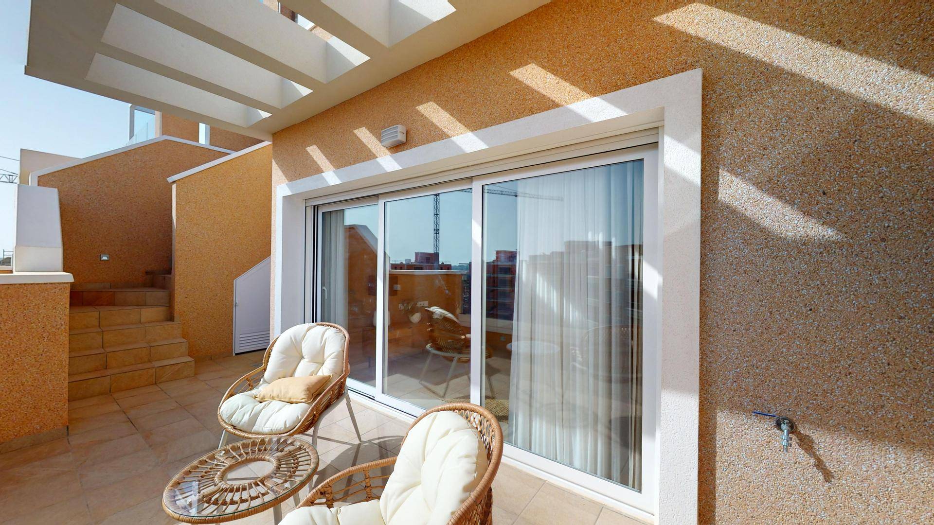 Sonnige Terrasse mit Korbmöbeln und Blick auf die Umgebung, ideal zum Entspannen.