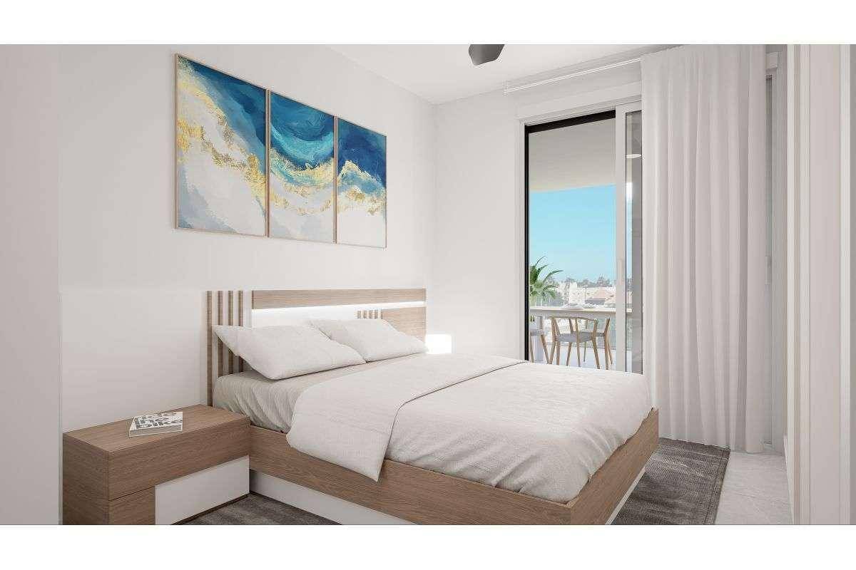 Helles Schlafzimmer mit modernem Holzbett, blauen Kunstwerken und Zugang zu einem Außenbereich.