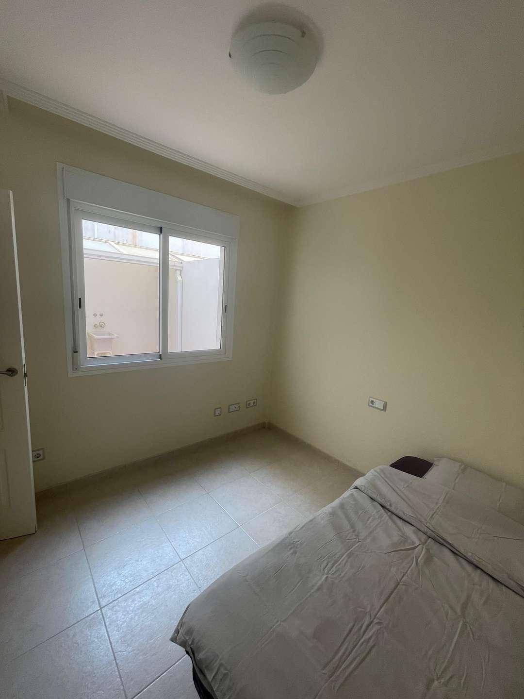 Schlafzimmer mit Einzelbett und Fenster, das Licht von einem kleinen Innenhof hereinlässt.