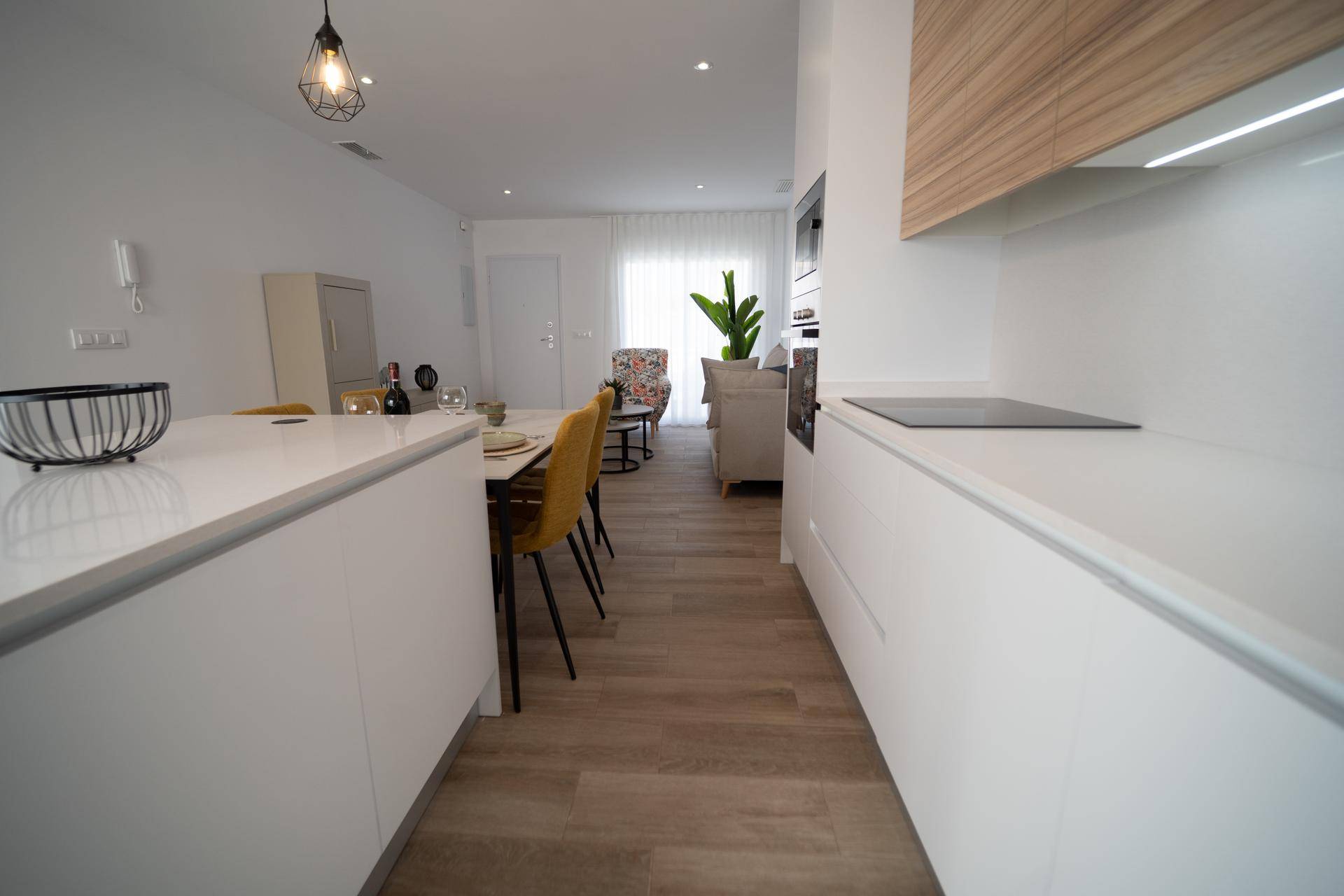 Heller offener Wohn-Essbereich mit moderner Küche, Holzboden und Zugang zur Terrasse.