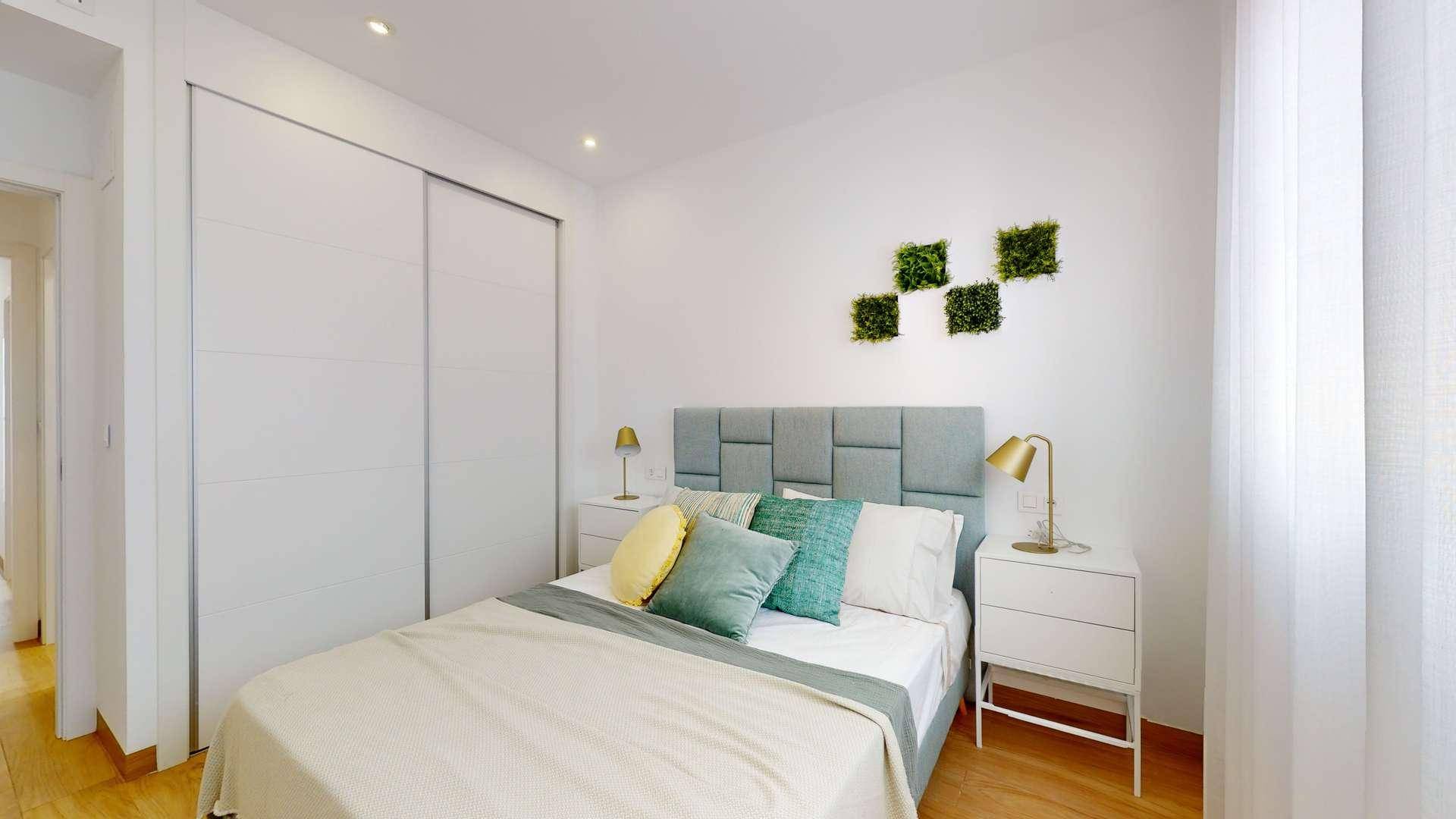 Modernes Schlafzimmer mit Doppelbett, Nachttischen und praktischem Einbauschrank.