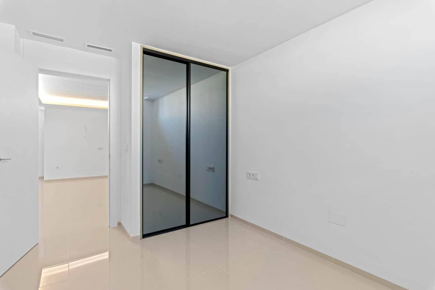 Heller Flur oder leeres Zimmer mit integriertem Spiegelschrank und glänzenden Fliesen.