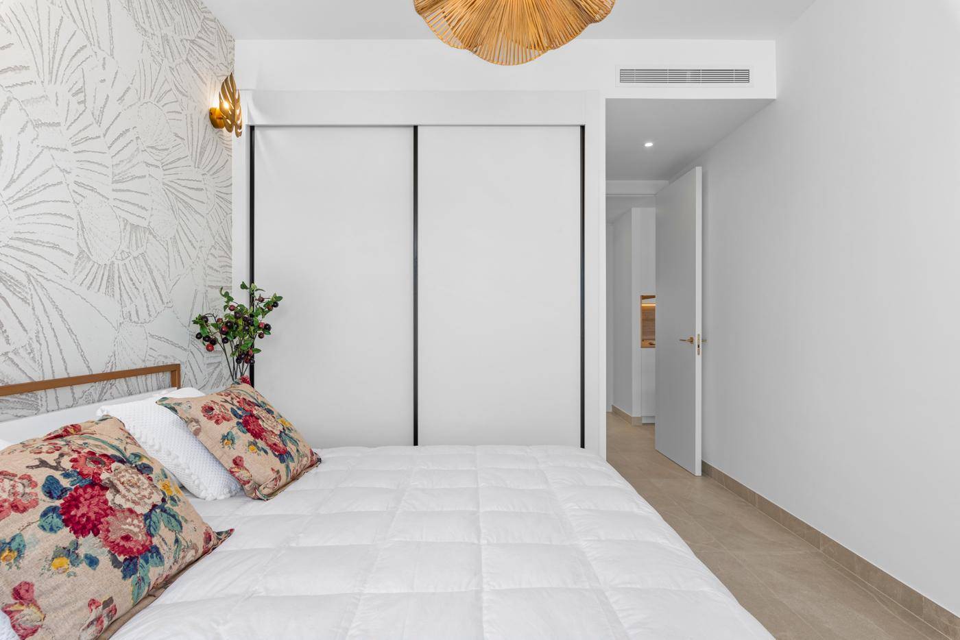 Schlafzimmer mit floraler Tapete, großem Bett und praktischen Einbauschränken.