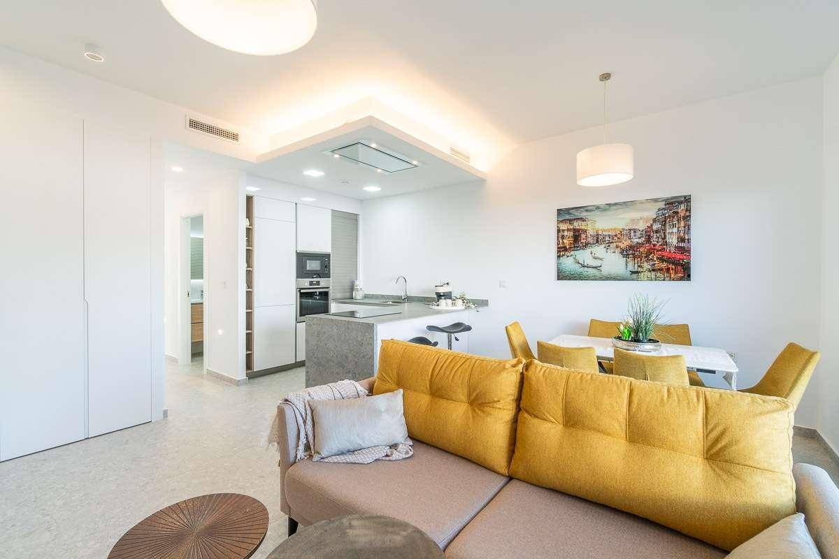 Geräumiger Wohn-Essbereich mit offener Küche, beigem Sofa und Kunst an der Wand.