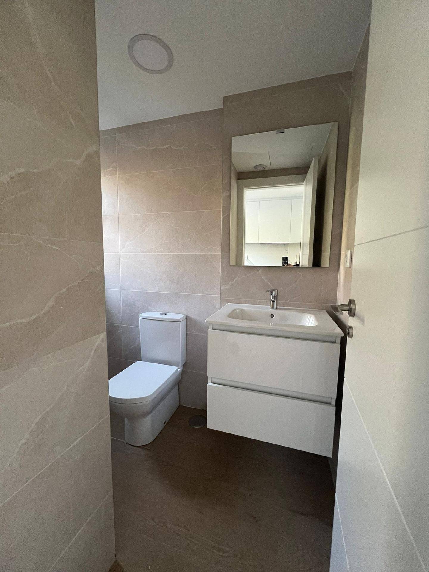 Modernes Badezimmer mit Wand-WC, Waschtisch und großen Fliesen an den Wänden.