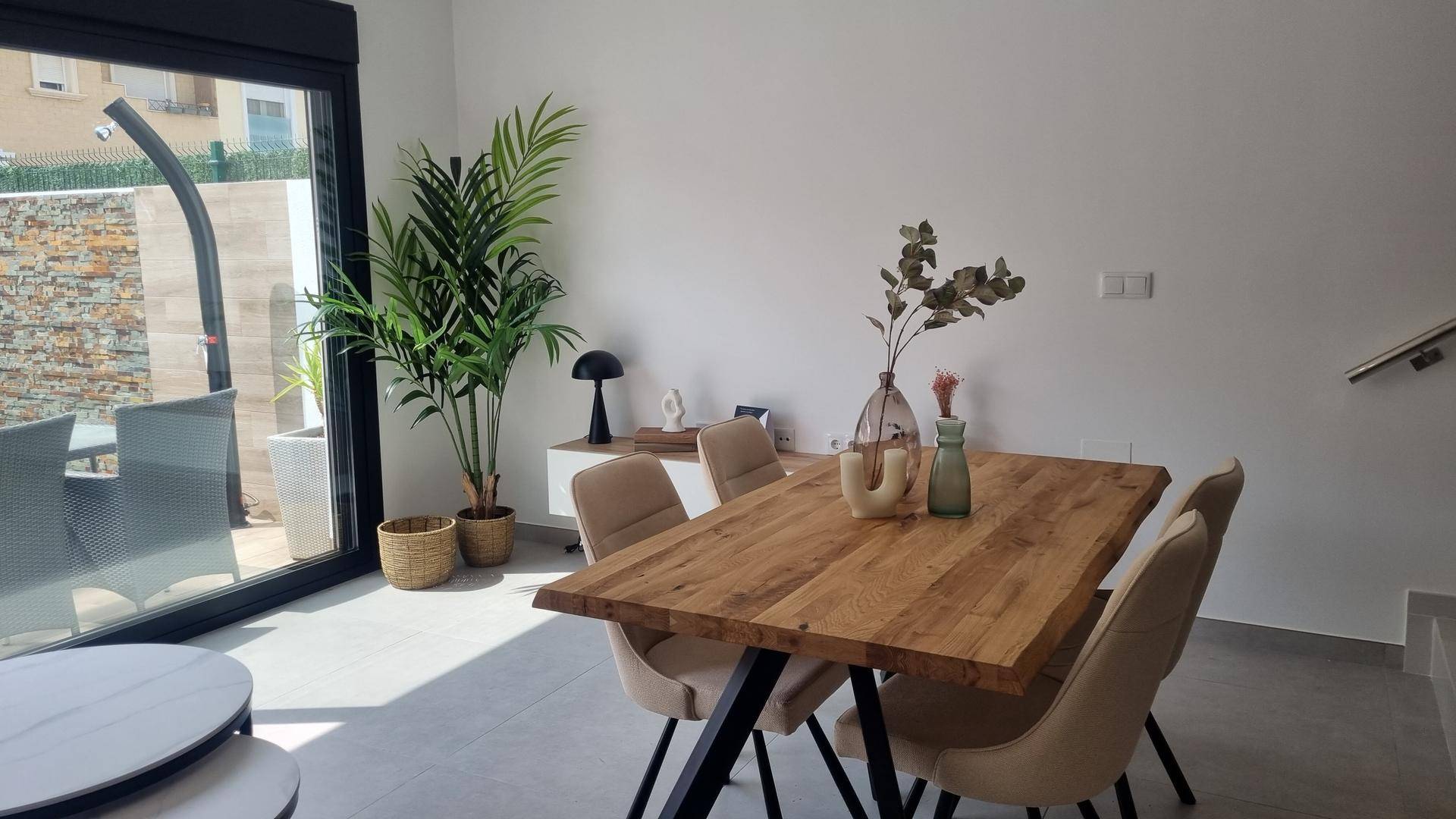 Heller Essbereich mit großem Holztisch, Pflanzen und Zugang zur Terrasse.