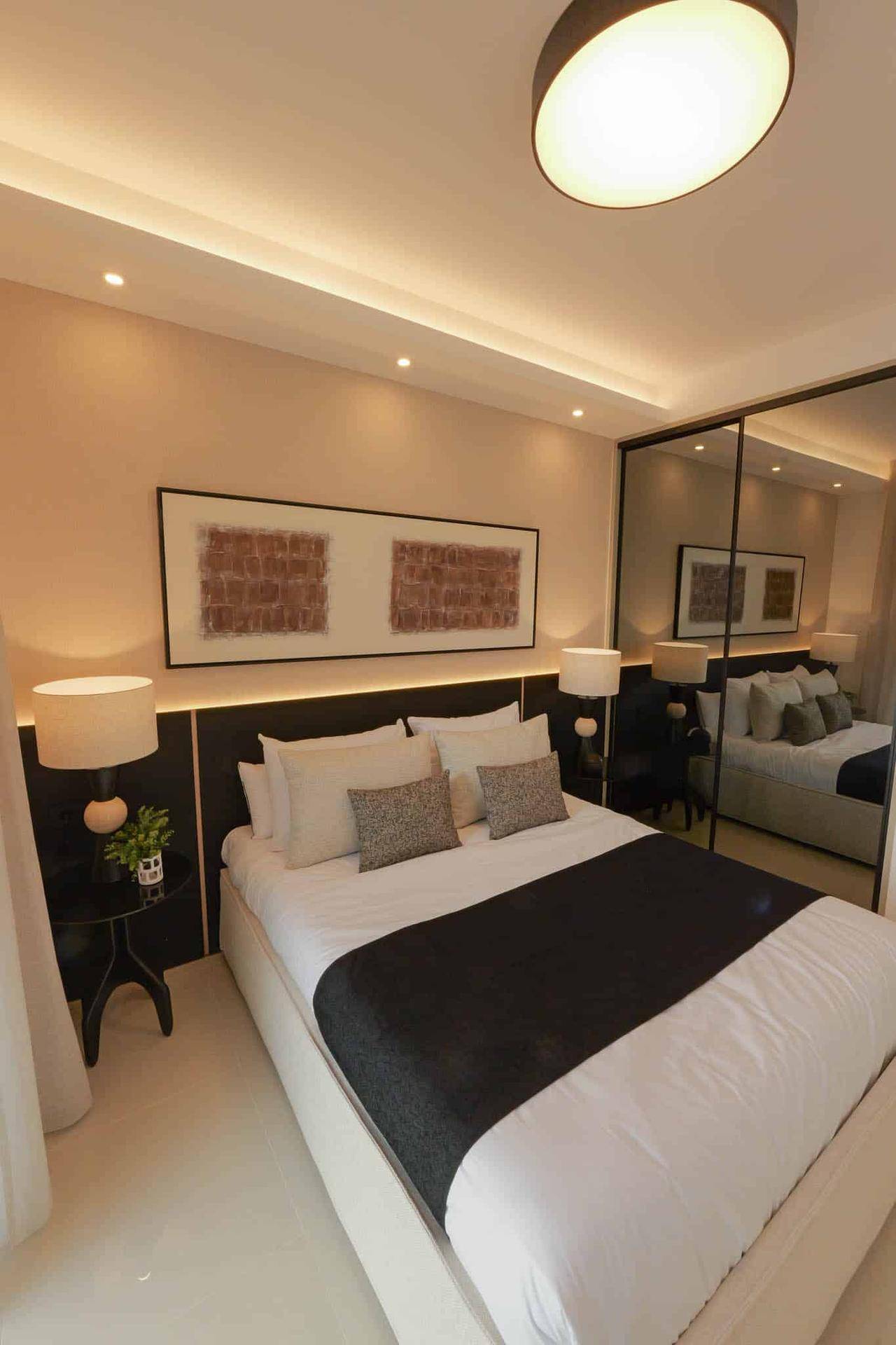 Stilvolles Schlafzimmer mit großem Bett, Spiegelschrank und indirekter Beleuchtung, schafft eine luxuriöse Atmosphäre.