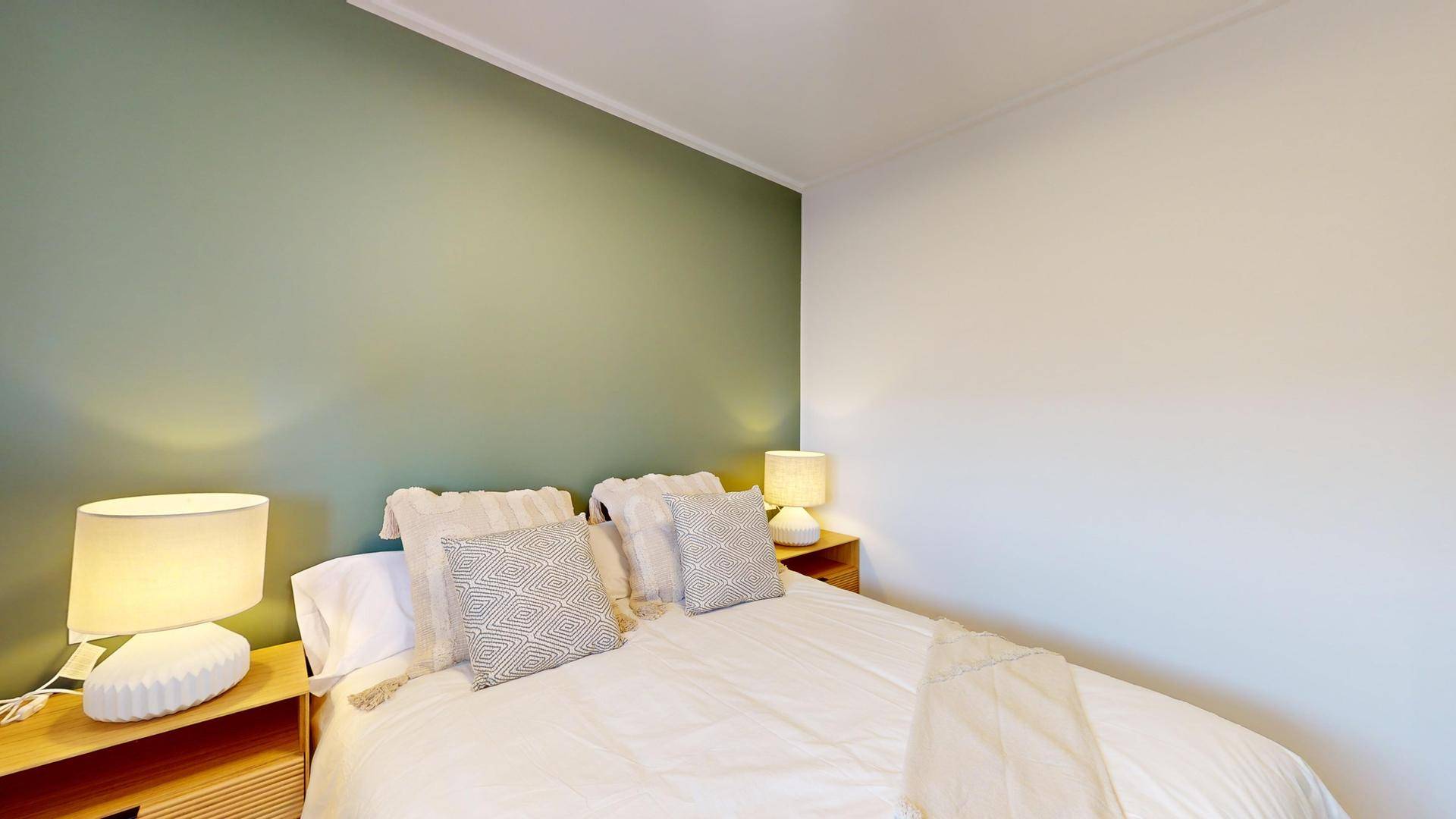 Gemütliches Schlafzimmer mit einer grünen Akzentwand und zwei Nachttischlampen für angenehmes Licht.