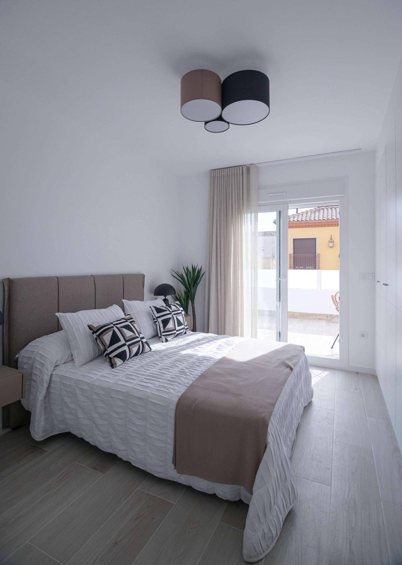 Helles Schlafzimmer mit Doppelbett, weißen Einbauschränken und Zugang zur Terrasse.
